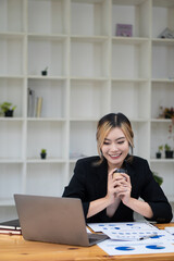 An Asian female accountant sits at a desk with financial graphs and calculators to make calculations that show results on investments. Plan a successful business growth process.