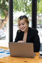 An Asian female accountant sits at a desk with financial graphs and calculators to make calculations that show results on investments. Plan a successful business growth process.