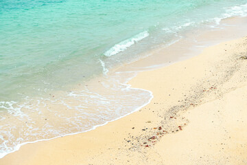 Clear water with small white waves hitting the light yellow beach