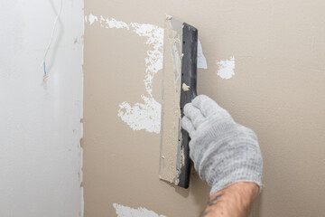 Man plastering wall with putty-knife, preparation for painting.Hands of worker with wall plastering tools renovating house. Plasterer renovating walls and corners with spatula.Copy space
