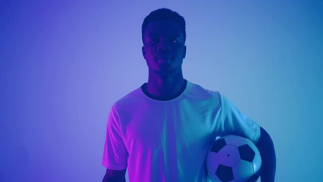 portrait of afro-american junior footballer in studio, young black man is holding ball