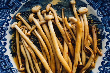 Sautéed Enoki Mushrooms with garlic, sesame oil, soy sauce, East Asian cooking on blue and white...
