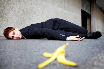 Sometimes banana skins are unavoidable. A young man lying on the ground after slipping on a banana peel.