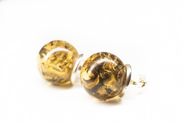 Sphere ball resin earrings with lichen. Bright yellow and brown plants preserverd in handmade piece of jewelry. Selective focus on the details, object isolated on white background.