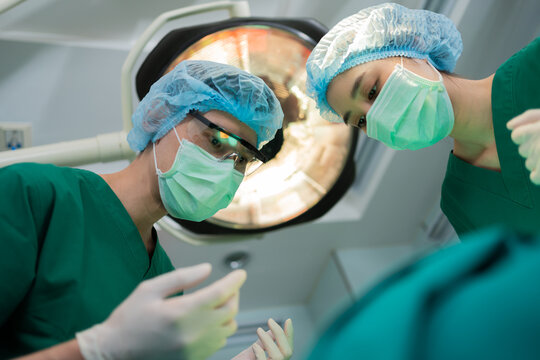 Low Angle Shot of Professional surgeons team performing surgery in operating room, surgeon, Assistants, and Nurses Performing Surgery on a Patient, health care cancer and disease treatment concept