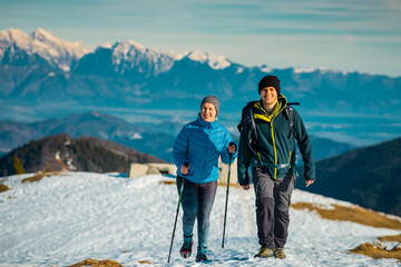 Young couple, male and female are hiking on a snow covered hill or mountain. Winter hike on Blegos,...