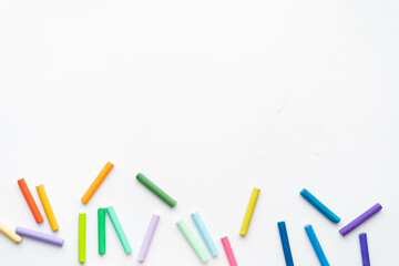 A set of pastel pencils of all colors of the rainbow scattered on a white background. place under...