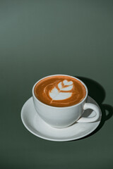 A cup of coffee and coffee beans on green background. Top view. Copy space