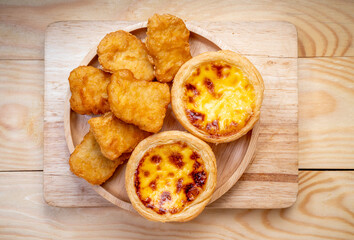 Fried chicken nuggets with egg tart on wooden background.