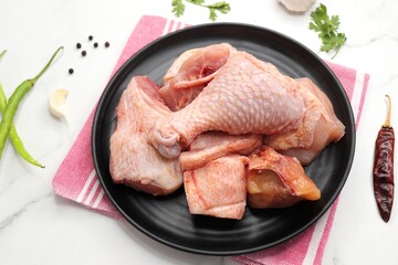 Clean and Raw Chicken on a black plate with Indian spices and cooking ingredients. Along with copy space. Chicken curry cut. Biryani cut chicken with skin on. complete animal based Protein source.