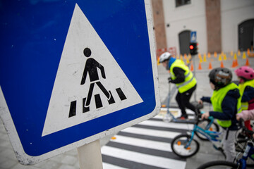 Zebra road signs many child with bicycle and roller scooter in background