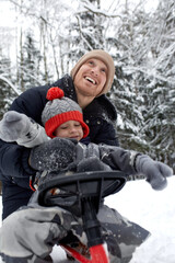 Fototapeta na wymiar Father and his son in funny hat having fun and laughing in snowy winter forest. Happy family wearing warm winter clothes enjoying wintertime in snow covered pine forest. Outdoor activities with kids.