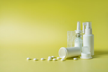 Medicine background with packs of pills, glass bottle, nasal spray and ampoules on the beige background with copy space
