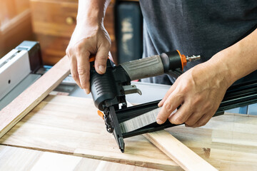 carpenter load nails into a nail gun ,furniture restoration woodworking concept. selective focus - obrazy, fototapety, plakaty