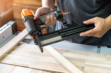 carpenter load nails into a nail gun ,furniture restoration woodworking concept. selective focus