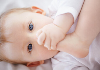 Theses things are pretty fun. Closeup portrait of an adorable baby lying down and playing with its feet.