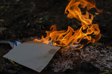 Burning in the fire of a torn notebook. The cover and the multi-colored sheets burn into gray ash.
