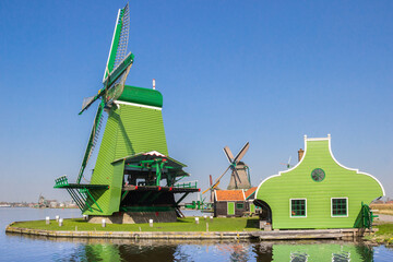 Fototapeta na wymiar Historic green windmill at the Zaan river in Zaanse Schans, Netherlands