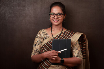 Portrait of a happy woman of Indian ethnicity wearing sari and holding tablet in hand