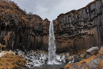 Cascada grande con nieve y columnas de basalto