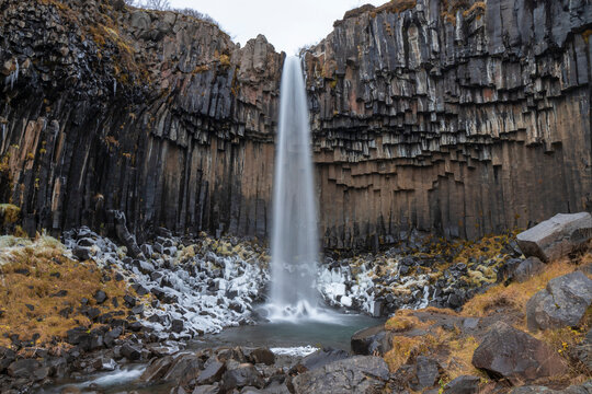 Cascada grande con nieve y columnas de basalto