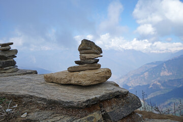 Prayer stone stacks with cloudy blue sky and green mountain view