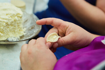 Women's hands in the process of making dumplings, ravioli or khinkali. The food of various peoples is dough with stuffing.