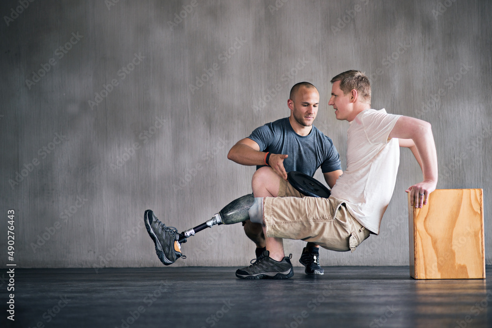 Wall mural Hes getting better by the day. Shot of a physiotherapist helping a young male amputee workout.