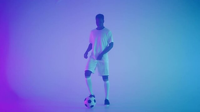 skilled afro-american footballer is dribbling ball in studio, showing professional skills