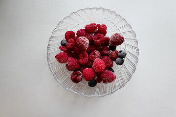 Frozen raspberries and chokeberries in a glass bowl