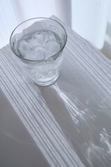 カーテンから差す光と氷と炭酸水が入ったグラス