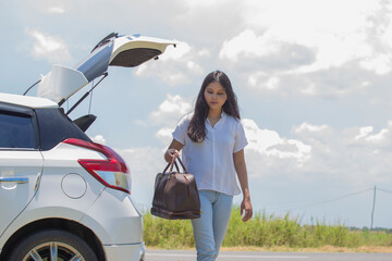 asian woman going to vacations, loading their car boot with travel suitcases
