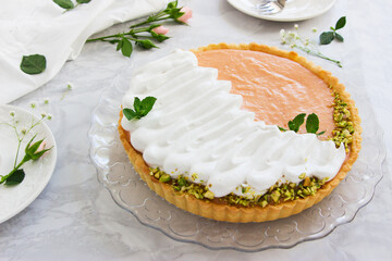 Grapefruit tart with whipped cream and pistachios on marble background.