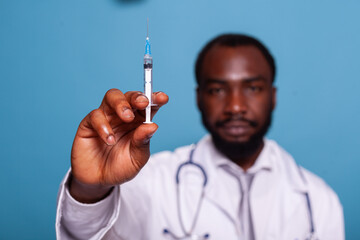 Closeup syringe with hypodermic needle containing medication cure drug in hand of confident doctor in white lab coat. Detail of shot with vaccine held by professional health care medic with