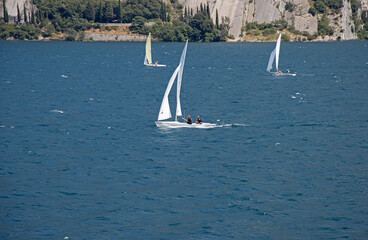 Obraz premium Small sailboats sail on Lake Lago di Garda in Italy