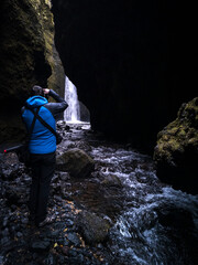Obraz premium Unrecognizable tourist taking photos to hidden waterfall in the narrow canyon