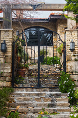close-up of a beautiful forged gate leading to an old stone house by stairs