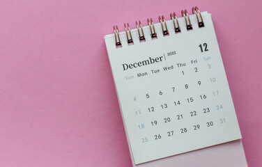 Desktop calendar for December 2022 on a pink background.