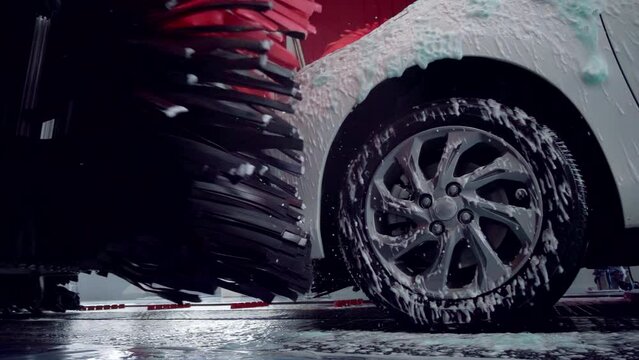 White car moving though automatic car wash machine. The brush moving to clean the car. Slow motion shot