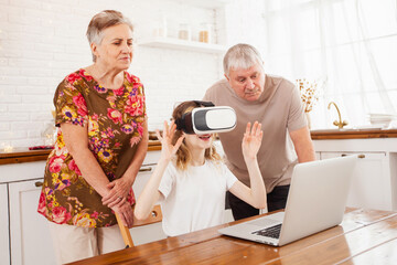 granddaughter with grandparents playing on a laptop and wearing virtual reality glasses