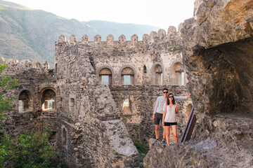 Young couple travelers in a castle standing on a rock