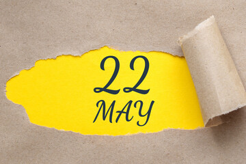 may 22. 22th day of the month, calendar date. Hole in paper with edges torn off. Yellow background is visible through ragged hole.Spring month, day of the year concept