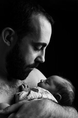 Father holds his newborn son with expression of affection