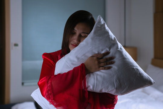 Female in satin nightwear and embracing soft pillow