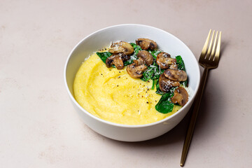 Polenta with mushrooms, spinach and cheese. Healthy eating. Vegetarian food. Italian cuisine.