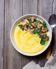 Polenta with mushrooms, spinach and cheese. Healthy eating. Vegetarian food. Italian cuisine.