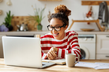 Happy african american woman smiling during online lesson while studying from home on laptop