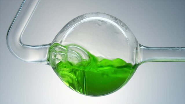 Green liquid boils in glass flask. Environmental pollution. Organic cosmetics. Concept. Water purification. Preparation of ingredients. Chemical experiment in laboratory. Boiling and steam. Toxicity.