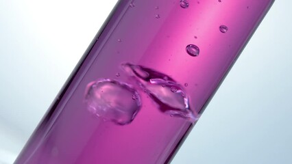 Glass test tube. Pink liquid in glass of  flask. Slow motion. Boiling and air bubbles in water. Cosmetics and perfumes. Extract from natural ingredients. Aromatherapy.
