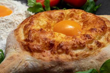 traditional Georgian dish: Adjarian khachapuri on a dark decorated background, hot fresh pastry